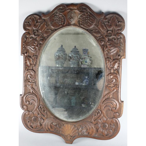 433 - A Carved Oak Wall Mirror in the Manner of Arthur Simpson, Kendal with Oval Bevelled Glass, 68x88cms