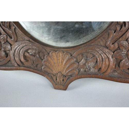 433 - A Carved Oak Wall Mirror in the Manner of Arthur Simpson, Kendal with Oval Bevelled Glass, 68x88cms