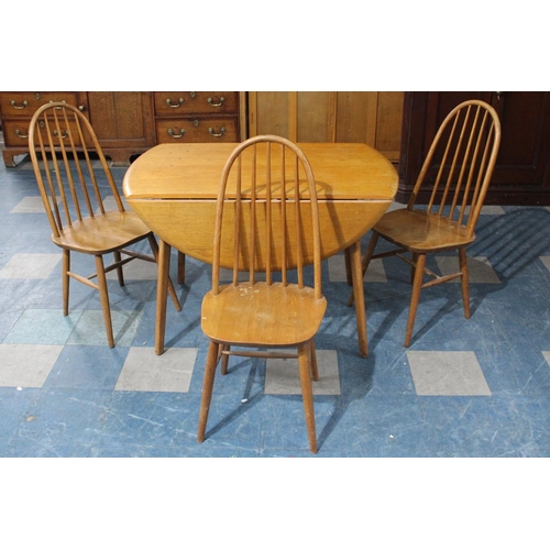 490 - A 1970's Drop Leaf Dining Table Together with Three Hooped Back Chairs in the Windsor Style