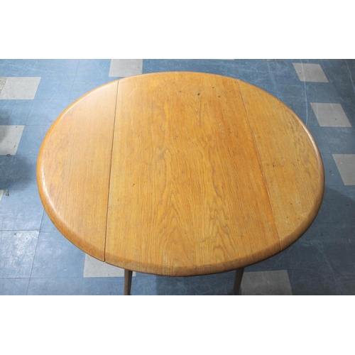 490 - A 1970's Drop Leaf Dining Table Together with Three Hooped Back Chairs in the Windsor Style