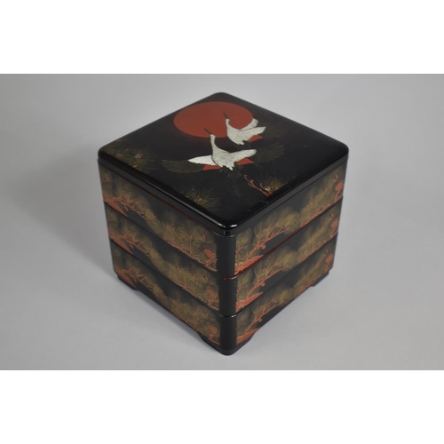 24 - A Modern Oriental Three Tier Lacquered Food Box Decorated with Cranes and Fir Cones, 20cms Square