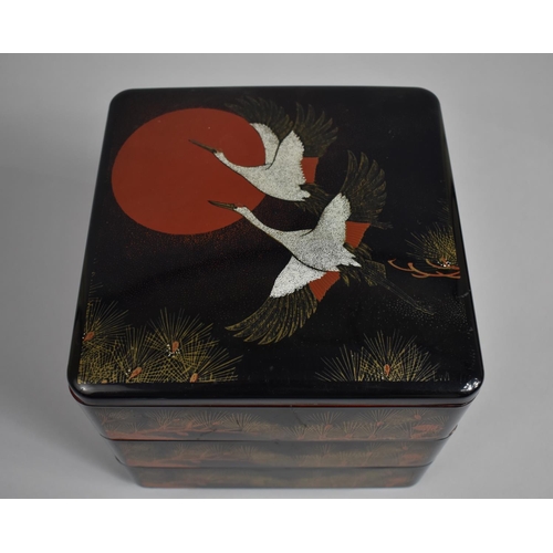 24 - A Modern Oriental Three Tier Lacquered Food Box Decorated with Cranes and Fir Cones, 20cms Square