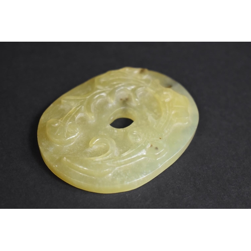 341 - A Chinese Green Hardstone Roundel with Floral Relief Carving, 7cm Wide.