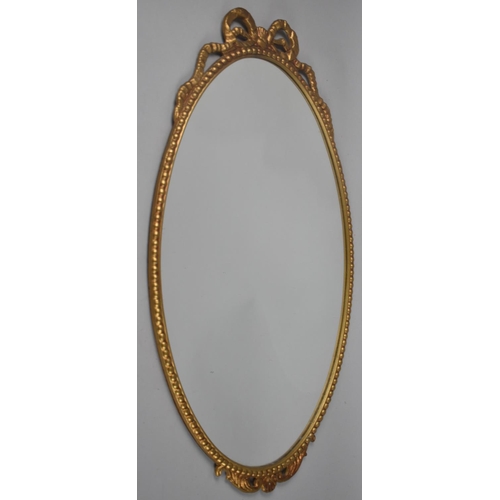 126 - A Mid 20th Century Gilt Metal Framed Oval Wall Mirror with Ribbon Finial, 64x38cms