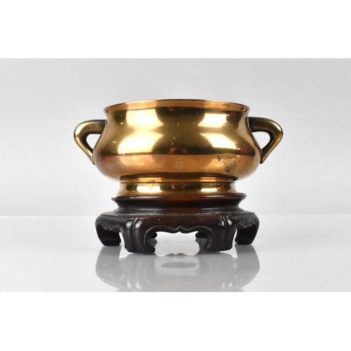 A Chinese Qing Dynasty Polished Bronze Censer of Compressed Bombe Form, with Flaring Foot and Rim and Applied to the sides with Twin Lug, With Two Character Marks To Base, Handles with Carved Wooden Stand. 862g 16x10.5X6.5cm