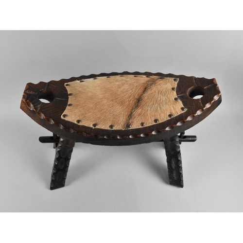 21 - A Carved Wooden Oval Topped Stool with Animal Skin Pad Seat, 46cms Wide