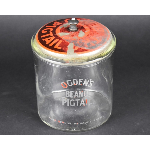 103 - An Ogden's Beano Pigtail Glass Advertising Pot with Painted Tin Plate Lid, 17cms High