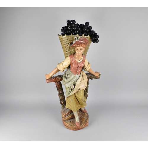 103 - A Large Cold Painted Terracotta Figure of Grape Picker with Basket on Vine Trellis, 54cms High