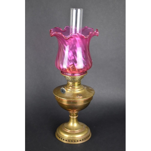 74 - An Early 20th Century Brass Oil Lamp with Cranberry Glass Shade and Plain Glass Chimney, 57cms High