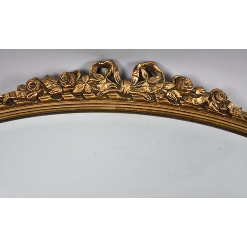 344 - An Oval Gilt Framed Bevelled Glass Wall Mirror with Rose and Ribbon Finial, 72x48cm