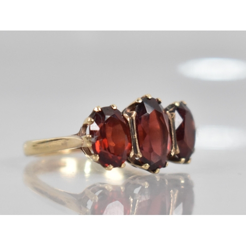 74 - A 9ct Gold and Garnet Dress Ring, Central Oval Cut Stone Measuring 9.9mm by 6.5mm, Claw and Tension ... 