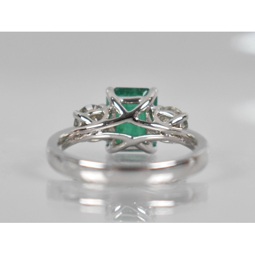 18 - An 18ct White Gold, Diamond and Emerald Three Stone Ring, Central Rectangular Step Cut Emerald Measu... 