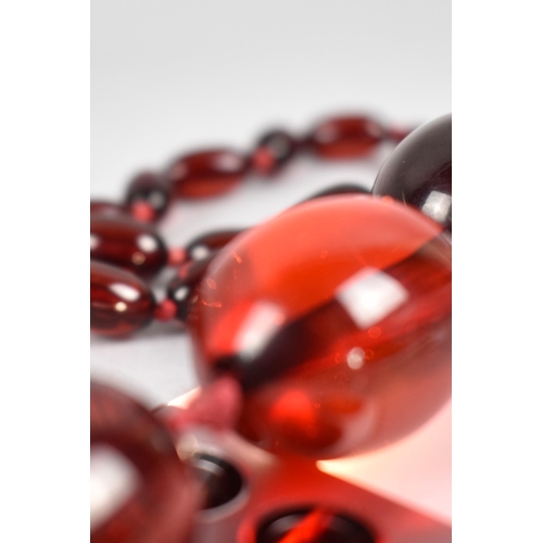 230 - A Long String of 58 Cherry Bakelite Beads, Largest 30mm Long by 21mm High, Smallest 13mm by 8mm, App... 