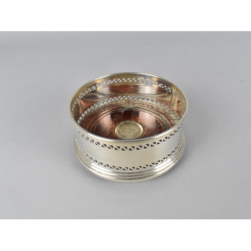 395 - A Silver Bottle Coaster with Pierced Trim and Turned Wooden Base with Silver Mount, 9cm diameter