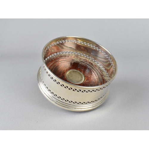 395 - A Silver Bottle Coaster with Pierced Trim and Turned Wooden Base with Silver Mount, 9cm diameter