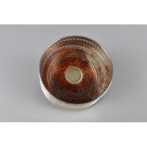 395 - A Silver Bottle Coaster with Pierced Trim and Turned Wooden Base with Silver Mount, 9cm diameter