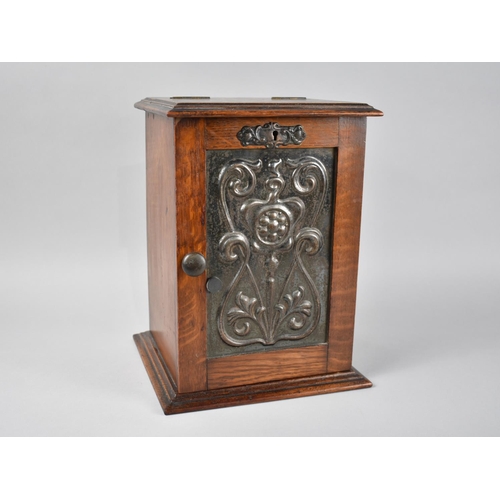 10 - An Art Nouveau Oak Smokers Cabinet, the Panelled Door with Metal Inset Having Relief Decoration, Bas... 