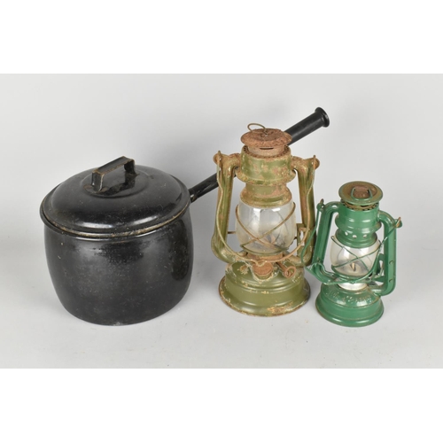 244 - An Enamelled Metal Cooking Pan and Two Hurricane Lamps