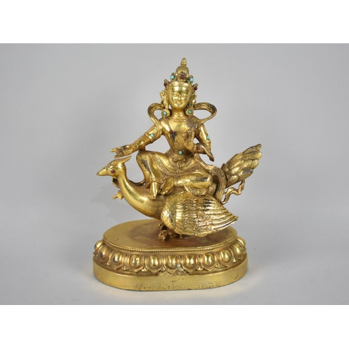 65 - A Gilt Bronze Jewelled Figure of a Seated Buddha Riding on Peacock, Oval Lotus Throne Base