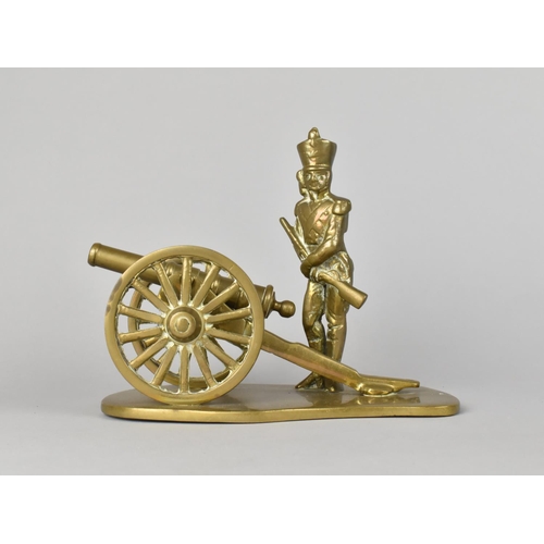 30 - A Brass Ornament of Soldier Standing Beside Field Cannon, 19cms Long