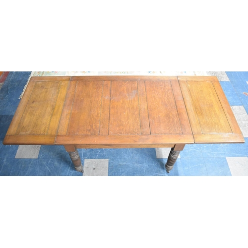 545 - An Edwardian Oak Drawer Leaf Dining Table On Turned Reeded Supports Culminating in Casters, Extends ... 