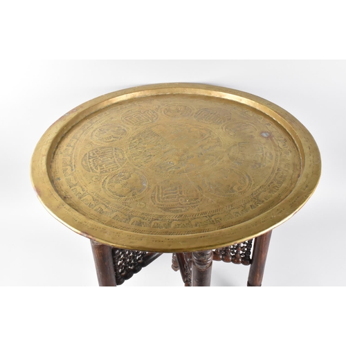 75 - An Engraved Brass Benaries Tray on Folding Wooden Stand, 56.5cms Diameter, Islamic Decoration to Top