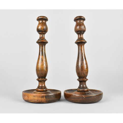 110 - A Pair of Edwardian Oak Candlesticks with Circular Tray Bases, 26cms High