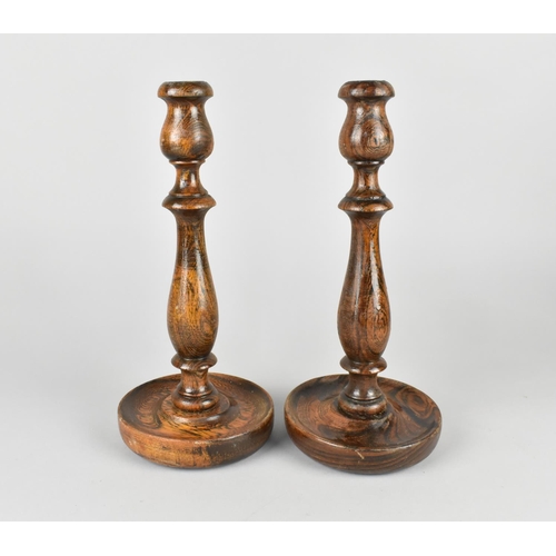 110 - A Pair of Edwardian Oak Candlesticks with Circular Tray Bases, 26cms High