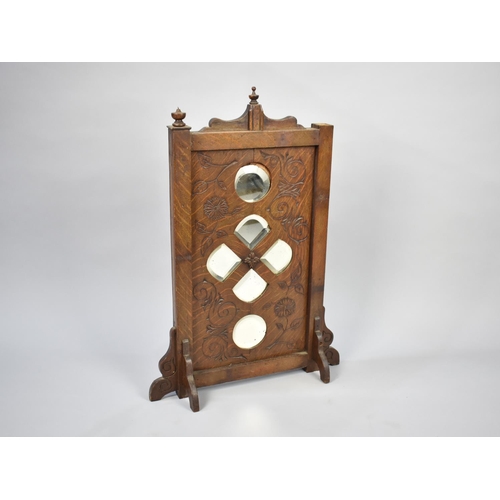 64 - An Edwardian Oak Screen with Bevelled Glass Inserts and Carved Decoration, in the Gothic Revival Sty... 