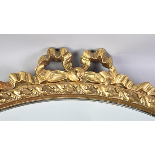 307 - An Oval Gilt Framed Mirror with Bow Finial, 54x50cm