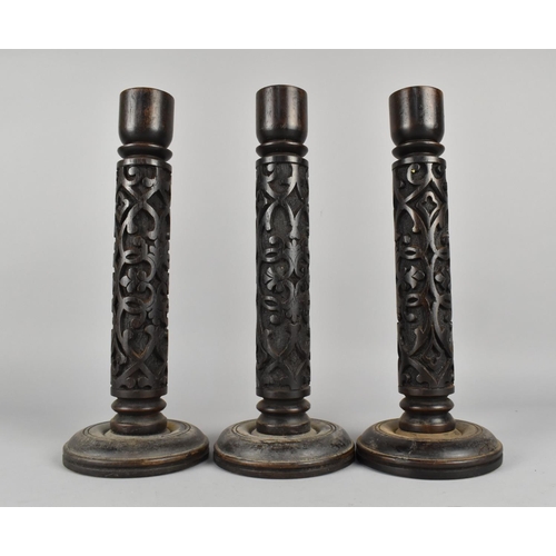 122 - A Set of Three Indian Blind Carved Wooden Candlesticks, 34cms High