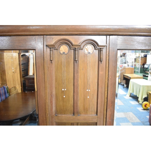 473 - An Arts and Crafts Influenced Oak Triple Wardrobe with two Base Drawers, Two Mirrored Doors to hangi... 