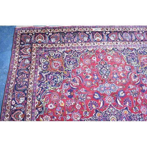 492 - A Large Patterned Rug on Red Ground, 395x285cms