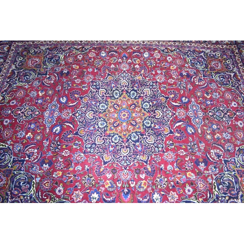 492 - A Large Patterned Rug on Red Ground, 395x285cms