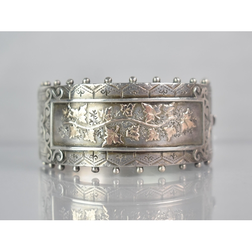 264 - A Victorian Silver Aesthetic Hinged Bangle, Central Rectangular Cartouche with Gilt Metal Ivy/Maple ... 