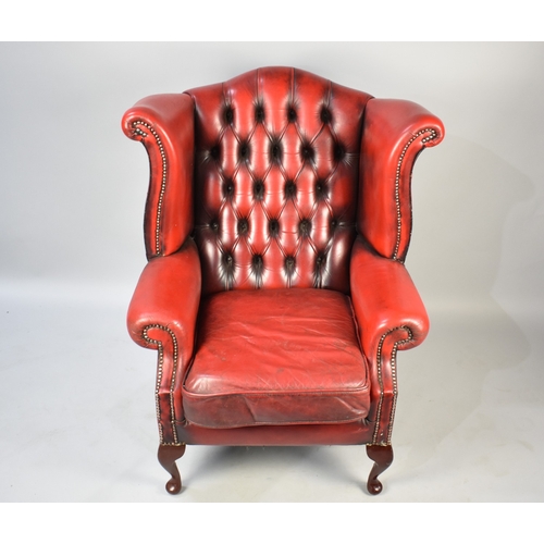 519 - A Mid Century Red Leather Style Wing Armchair with Button Back, 88x107cm high