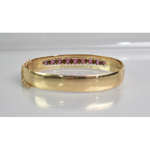 12 - A Ruby and Diamond Set 9ct Gold Hinged Bangle, Nine Graduated Oval Cut Rubies, Largest 5.1mm by 2.8m... 