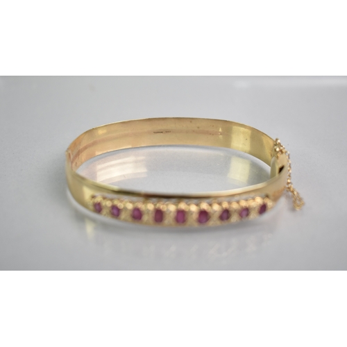 12 - A Ruby and Diamond Set 9ct Gold Hinged Bangle, Nine Graduated Oval Cut Rubies, Largest 5.1mm by 2.8m... 