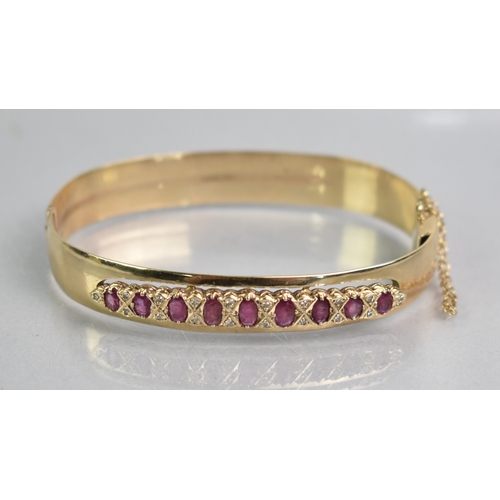 12 - A Ruby and Diamond Set 9ct Gold Hinged Bangle, Nine Graduated Oval Cut Rubies, Largest 5.1mm by 2.8m... 