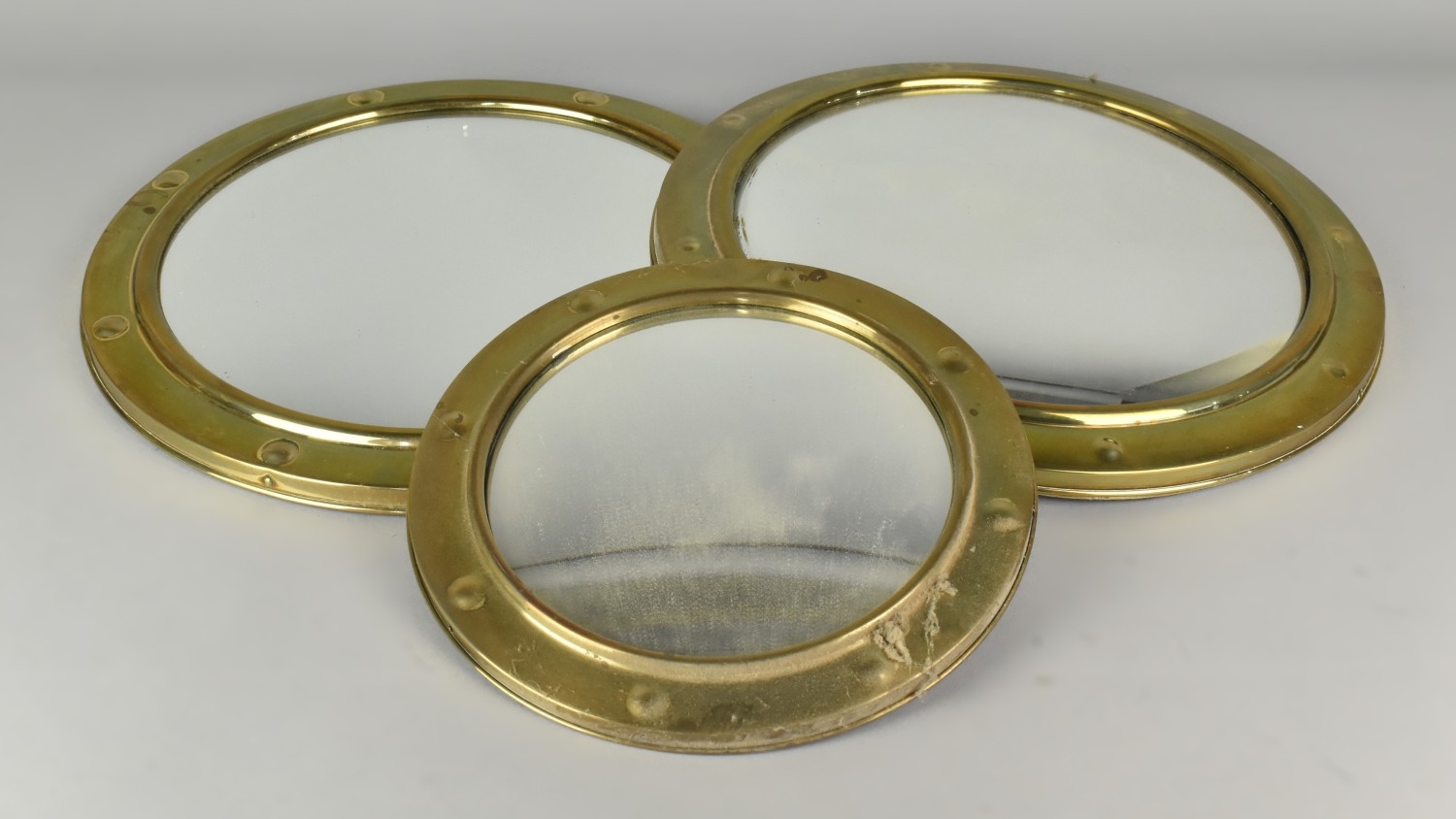 Three Graduated Brass Framed Convex Wall mirrors, the larger 36cm diameter