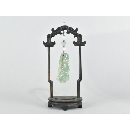 29 - A Chinese Jade Effect Pendant in Carved Wooden Arched Stand, 18.5cms High
