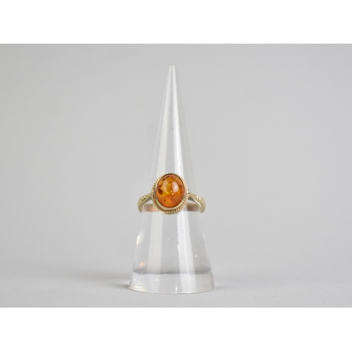 46 - A 9ct Gold and Amber Cabochon Ring, Bezel Set and with a Rope Twist Frame to Tapered Shoulders and a... 