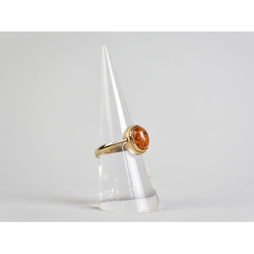 46 - A 9ct Gold and Amber Cabochon Ring, Bezel Set and with a Rope Twist Frame to Tapered Shoulders and a... 