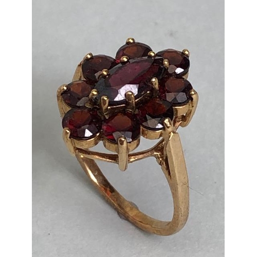 60 - 9ct gold daisy style ring set with nine garnets in claw settings with large oval central garnet on r... 