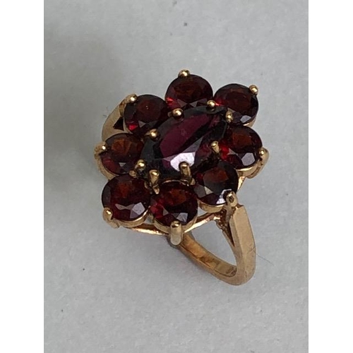 60 - 9ct gold daisy style ring set with nine garnets in claw settings with large oval central garnet on r... 