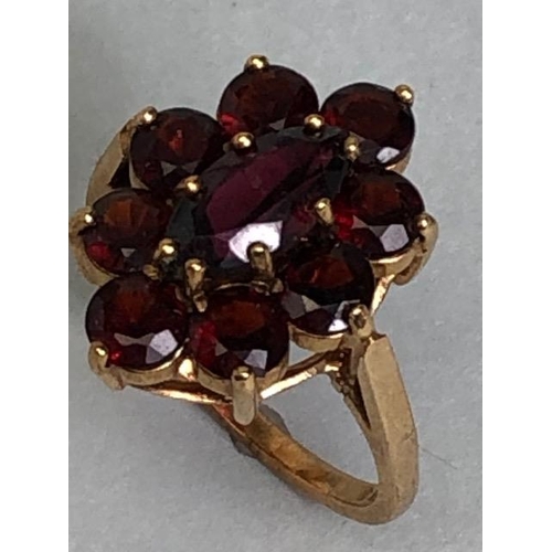 60 - 9ct gold daisy style ring set with nine garnets in claw settings with large oval central garnet on r... 