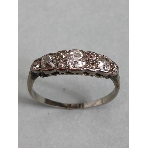 70a - Unmarked white Gold Diamond ring set with nine diamonds, the largest central diamond flanked by a pa... 