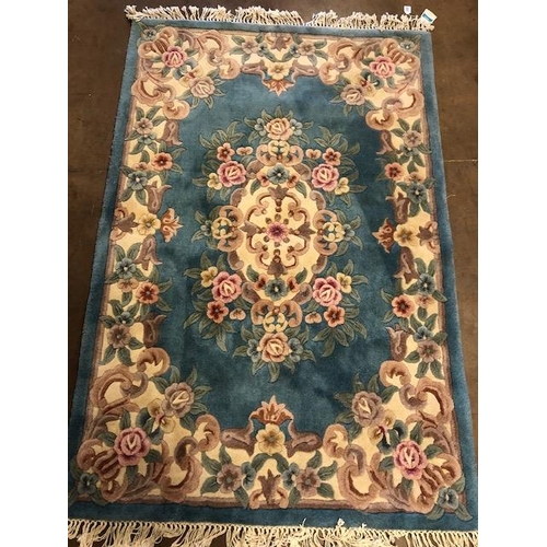 359 - Chinese wool rug of sculpted style with typical designs of flowers and  against a blue grey  back gr... 