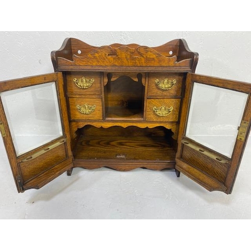 413 - Antique Smokers cabinet, in light oak, part glazed doors opening to show drawers and pipe rack  appr... 