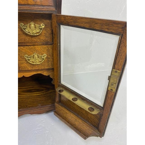 413 - Antique Smokers cabinet, in light oak, part glazed doors opening to show drawers and pipe rack  appr... 